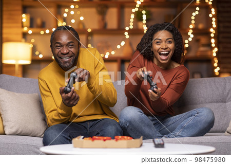 Emotional black couple playing video games at home Emotional black couple playing video games at home 98475980