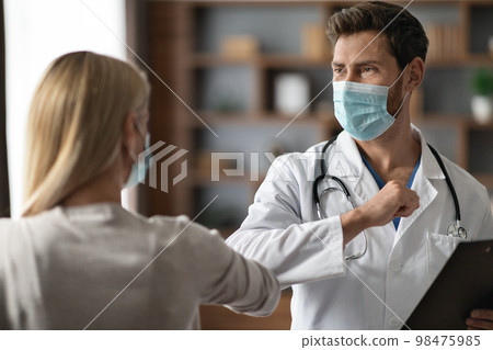 Male Doctor In Medical Mask Making Elbow Bump Greeting With Female Patient Male Doctor In Medical Mask Making Elbow Bump Greeting With Female Patient 98475985
