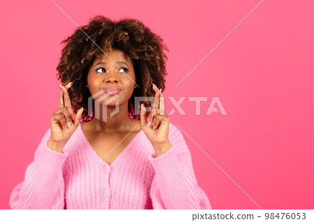 Cheerful millennial african american curly lady in casual crossed fingers, make wish isolated on pink background Cheerful millennial african american curly lady in casual crossed fingers, make wish isolated on pink background 98476053