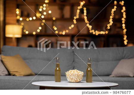 Glass bowl of popcorn and two bottles of beer Glass bowl of popcorn and two bottles of beer 98476077