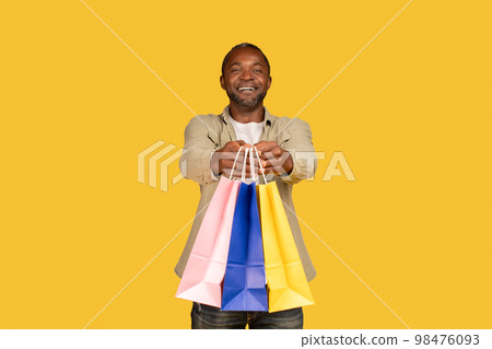 Cheerful african american middle aged man shopaholic show many packages with purchases from shop Cheerful african american middle aged man shopaholic show many packages with purchases from shop 98476093