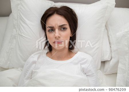 Unhappy young woman lying in bed at home, copy space Unhappy young woman lying in bed at home, copy space 98476209