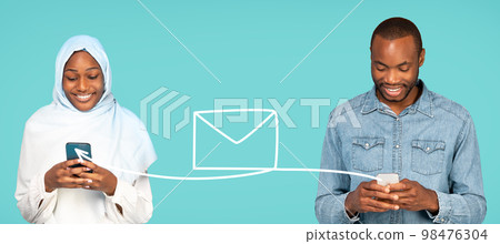 Black Man And Muslim Woman In Hijab Communicating Online On Smartphones 98476304