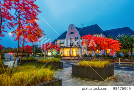 Garden in potted plants with autumn leaf color , red leaves, next to factory in Leverkusen and old building in distance Garden in potted plants with autumn leaf color , red leaves, next to factory in Leverkusen and old building in distance 98476969
