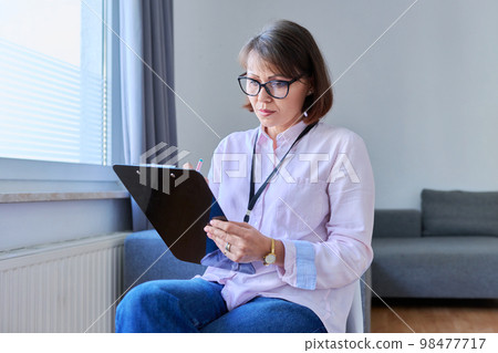 Portrait of middle aged female therapist with clipboard in office 98477717