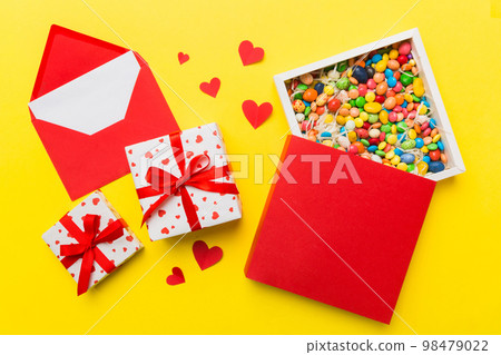 Red envelope with candy and gift box and Valentines hearts on colored background. Flat lay, top view. Romantic love letter for Holiday concept 98479022