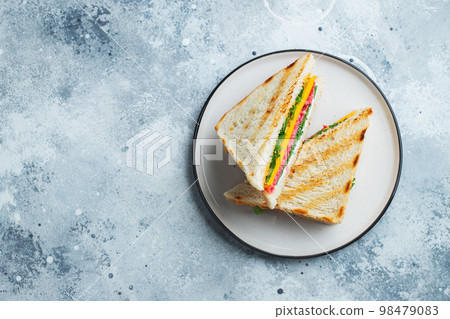 Two homemade sandwiches with sausage, cheese and arugula on a light concrete background Two homemade sandwiches with sausage, cheese and arugula on a light concrete background 98479083