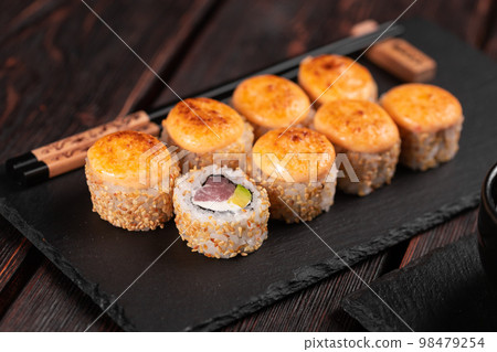 Sushi roll with tuna, avocado and tobiko caviar served on black board close-up - Japanese asian food 98479254