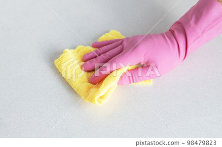 a hand in a pink glove wipes the surface with yellow microfiber 98479823
