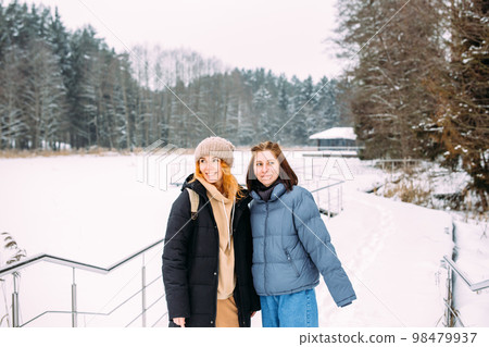 Two women friends in winter in nature in the park on a cold day Two women friends in winter in nature in the park on a cold day 98479937