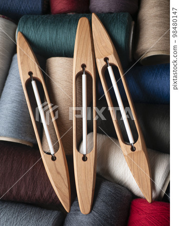 Wooden boat shuttles and bobbins with colored yarn. Weaving shuttles, vertical format Wooden boat shuttles and bobbins with colored yarn. Weaving shuttles, vertical format 98480147
