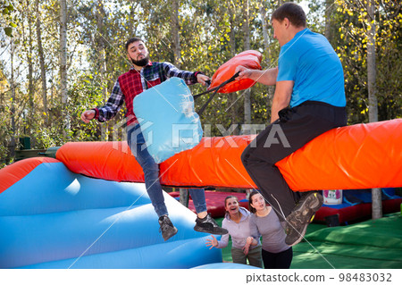 Males fighting on log at outdoor amusement playground Males fighting on log at outdoor amusement playground 98483032