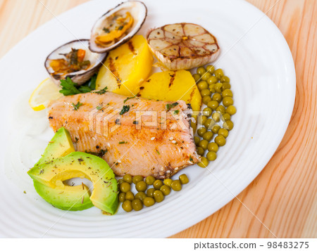 Fried trout fillets served with vegetables, seashells and avocado at plate Fried trout fillets served with vegetables, seashells and avocado at plate 98483275