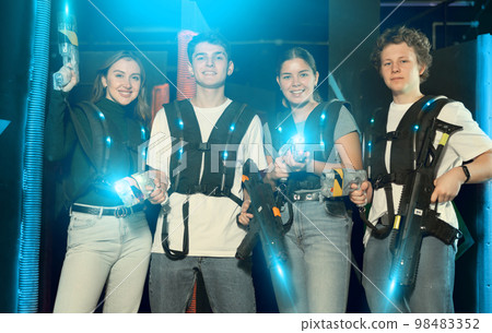 Two girls and two guys posing with lasertag guns in arena Two girls and two guys posing with lasertag guns in arena 98483352