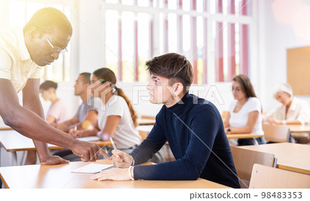 Professor explaining task solution to young man in college 98483353