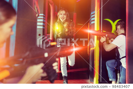 Girl running and dodging while playing lasertag 98483407