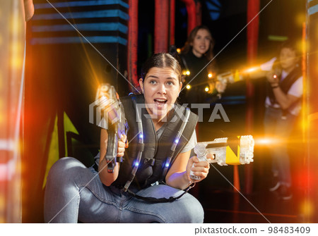 Girl running and dodging while playing lasertag Girl running and dodging while playing lasertag 98483409