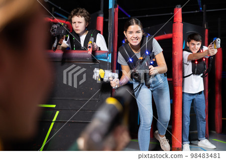 Laser tag players young mens and womens playing in teams in dark laser tag station Laser tag players young mens and womens playing in teams in dark laser tag station 98483481