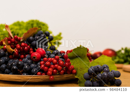 Autumn composition of blue grapes and viburnum on a plate Autumn composition of blue grapes and viburnum on a plate 98484110