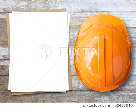 orange safety helmet and white paper on wood table background. 98485010