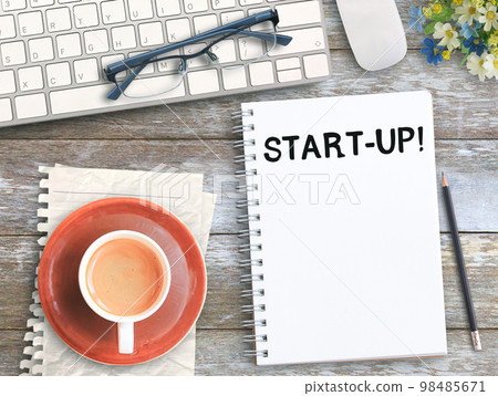 Top view with start up on notebook,keyboard,coffee and glasses on wood table i Top view with start up on notebook,keyboard,coffee and glasses on wood table i 98485671