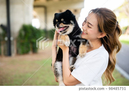 Happy young asian woman playing and sitting on road in the park with her dog. Pet lover concept Happy young asian woman playing and sitting on road in the park with her dog. Pet lover concept 98485731