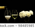 Festive party concept, Pour champagne from bottle into glass with peony in vase on black background 98485985