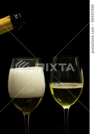 Champagne with party concept, Pour champagne from bottle into glass on black background Champagne with party concept, Pour champagne from bottle into glass on black background 98485986