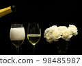 Festive party concept, Pour champagne from bottle into glass with peony in vase on black background 98485987
