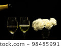 Festive party concept, Pour champagne from bottle into glass with peony in vase on black background 98485991