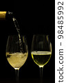 Champagne with party concept, Pour champagne from bottle into glass on black background 98485992
