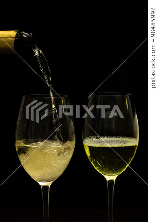 Champagne with party concept, Pour champagne from bottle into glass on black background Champagne with party concept, Pour champagne from bottle into glass on black background 98485992