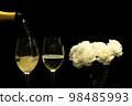 Festive party concept, Pour champagne from bottle into glass with peony in vase on black background 98485993