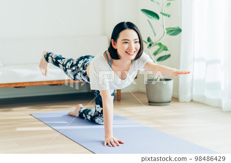 年輕女子在客廳裡做瑜伽 98486429
