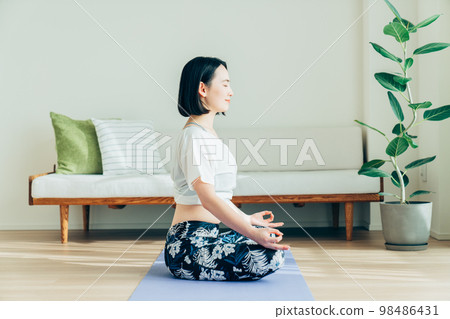 年輕女子在客廳裡做瑜伽 年輕女子在客廳裡做瑜伽 98486431