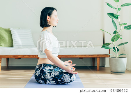 年輕女子在客廳裡做瑜伽 年輕女子在客廳裡做瑜伽 98486432
