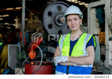 Portrait of woman engineer wear white helmet arms crossed in uniform standing at industrial. Portrait of woman engineer wear white helmet arms crossed in uniform standing at industrial. 98486514
