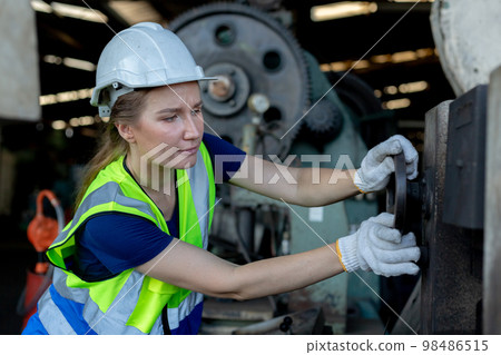 woman engineer wear hardhat working at machine in factory. woman engineer wear hardhat working at machine in factory. 98486515