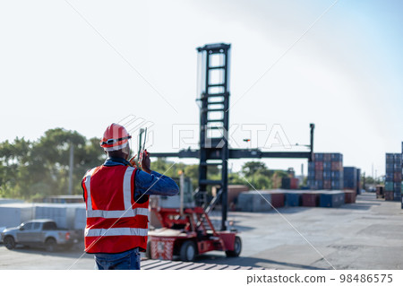 Foreman using radio communication control loading containers in shipping yard, 98486575