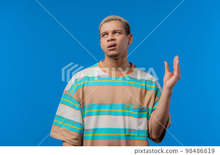 Irritated american man showing bla-bla-bla gesture with hands, rolling eyes on blue background Irritated american man showing bla-bla-bla gesture with hands, rolling eyes on blue background 98486819