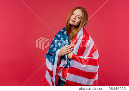 Smiling woman with national USA flag on pink background. American patriot, 4th of July - 98486923