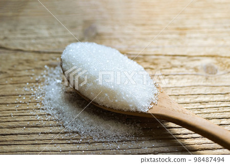 Sugar on spoon and wooden background, white sugar for food and sweets dessert candy heap of sweet sugar crystalline granulated 98487494