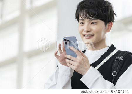 有智能手機的一個微笑的年輕人 有智能手機的一個微笑的年輕人 98487965