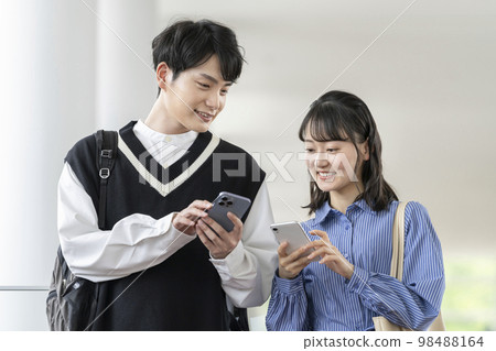 兩個年輕男女看著對方的智能手機屏幕 98488164