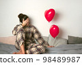 Depressed woman with an inflatable balloon on Valentine's Day. Front view.  98489987