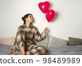 Depressed woman with an inflatable balloon on Valentine's Day. Front view.  98489989