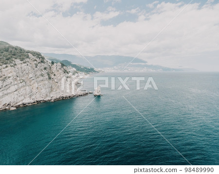 aerial photo of rock Parus Sail and Ayu-Dag Bear Mountain and near Gaspra, Yalta, Crimea at bright sunny day over the Black sea. Rock Parus in Gaspra near Swallow's nest in Crimea. 98489990