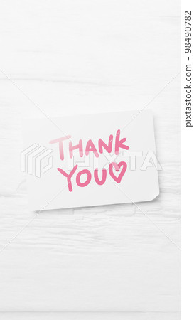 White paper on white wood background. Handwritten letter of THANK YOU written with a pink pen. letter. (Vertical) White paper on white wood background. Handwritten letter of THANK YOU written with a pink pen. letter. (Vertical) 98490782