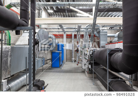 an long ventilation pipe in a technical room in the basement of a large building 98491028