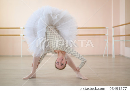 Beautiful young ballerina is rehearsing a solo part in a class with a barre. Slender graceful dancer is engaged before the performance. Beautiful young ballerina is rehearsing a solo part in a class with a barre. Slender graceful dancer is engaged before the performance. 98491277